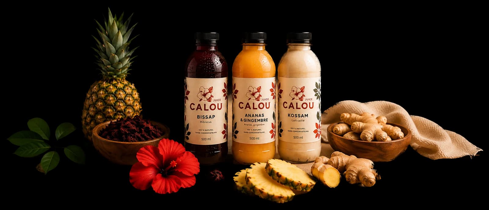 Les bouteilles Bissap, Ananas & Gingembre et Kossam, entourées d'ananas, de gingembre et de fleurs d'hibiscus.